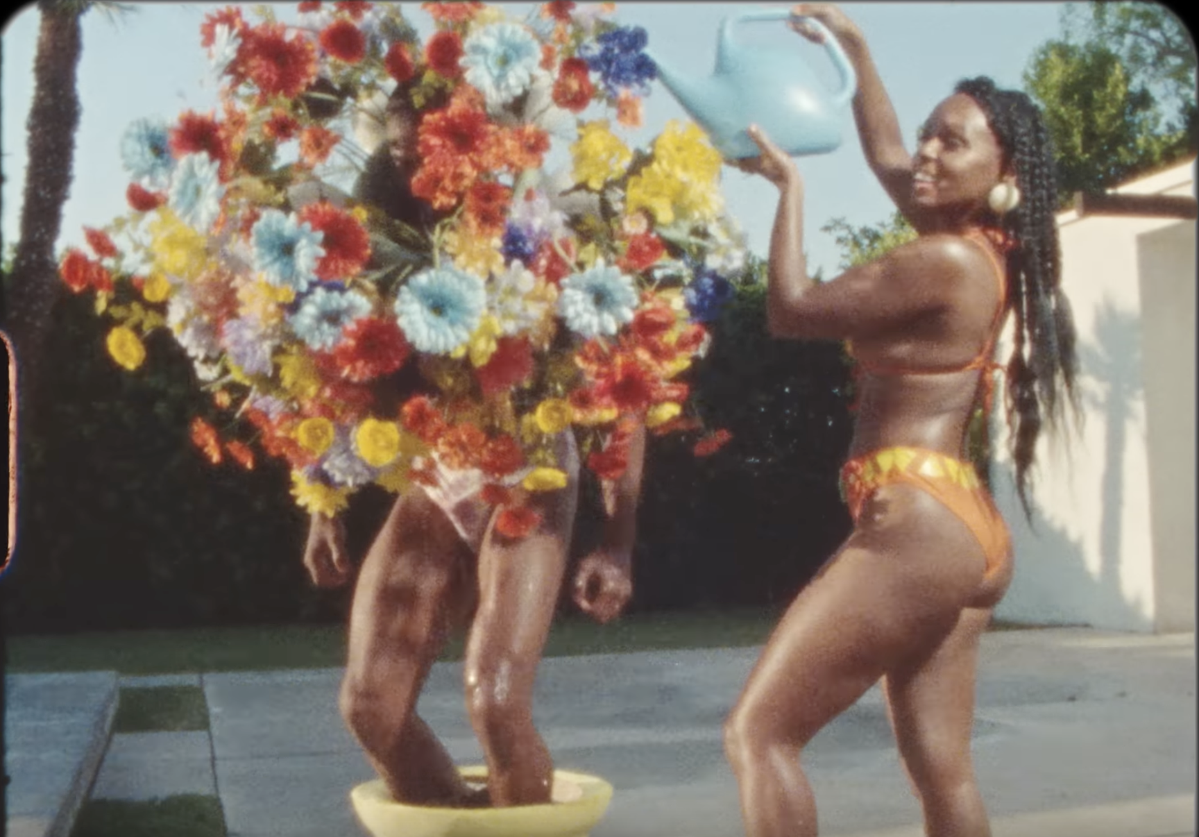 Janelle watering a man who is a flower.